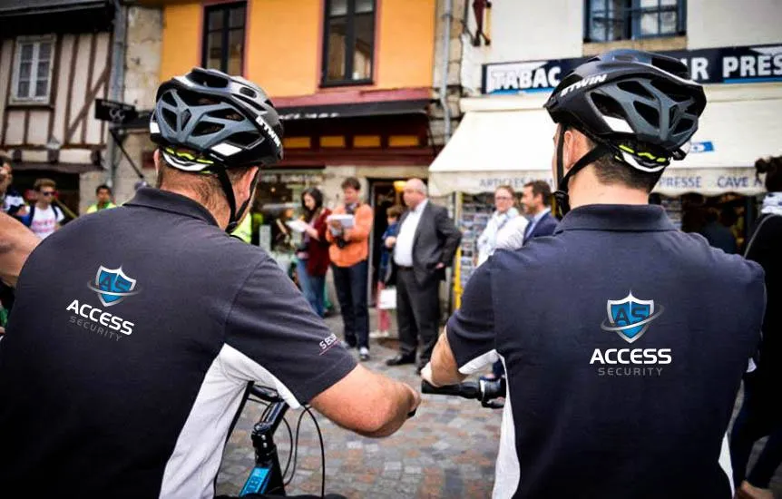 Deux agents de sécurité en vélo dans une rue animée.